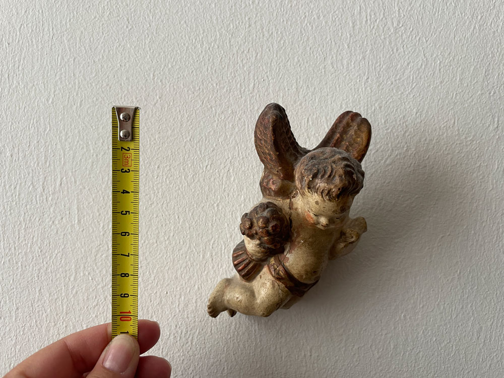 Inventarisierung: Ein Maßband neben einem alten Putto vor einer Wand